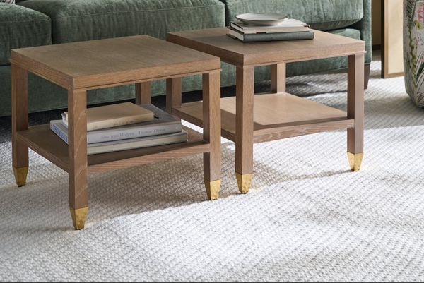 Paired oak side tables with brass feet in front of a green velvet sofa